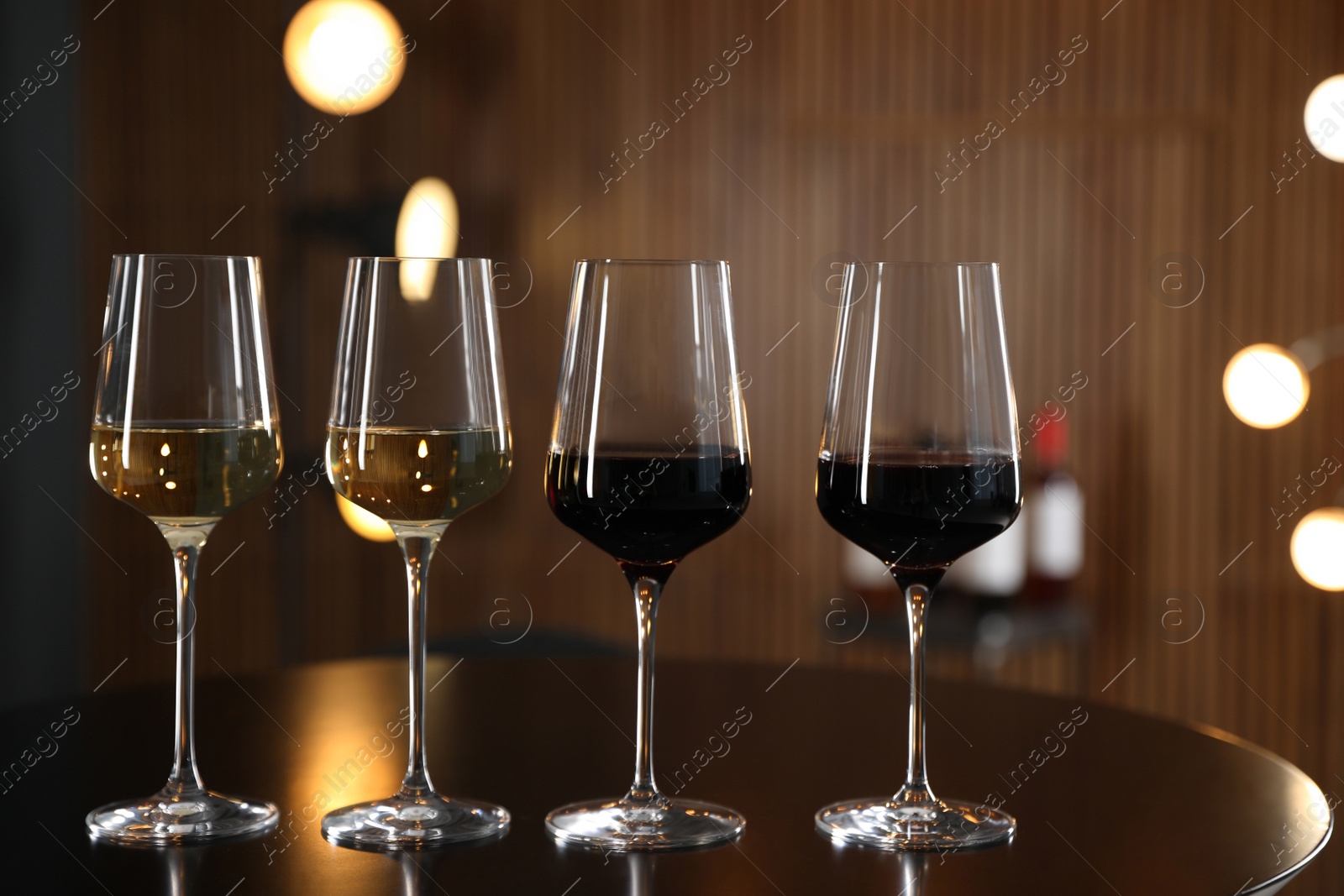 Photo of Glasses of different wines on table against blurred background