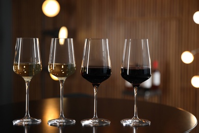 Glasses of different wines on table against blurred background