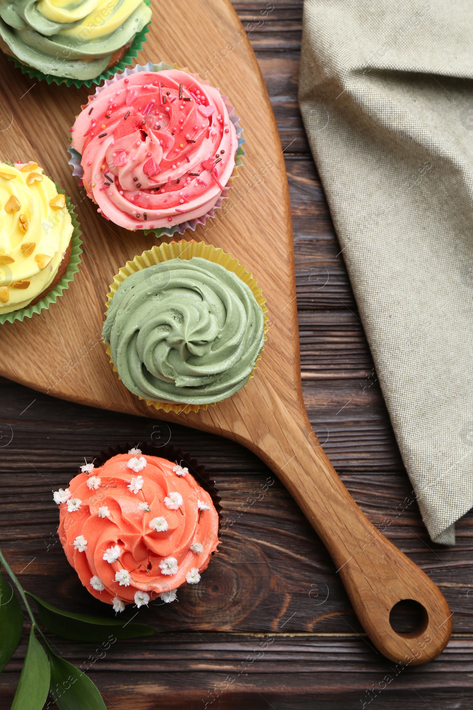 Photo of Delicious cupcake with bright cream on wooden table, flat lay