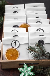 Photo of Paper bags, cookie and festive decor on wooden table, closeup. Christmas advent calendar