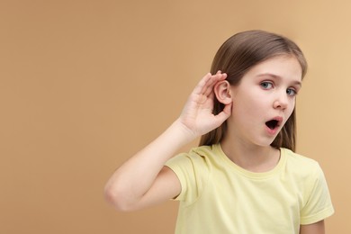 Photo of Little girl with hearing problem on pale brown background, space for text