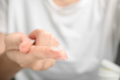 Photo of Woman with sample of cosmetic petrolatum on her finger, closeup. Space for text