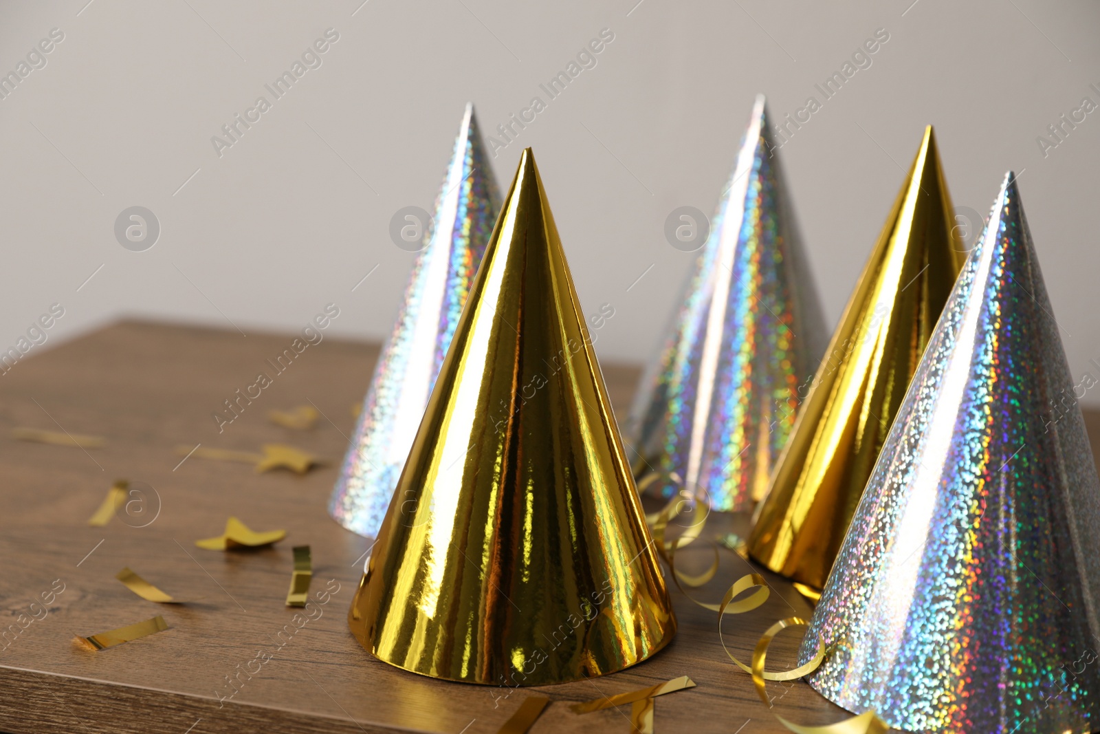 Photo of Birthday party hats, serpentine streamers and confetti on wooden table