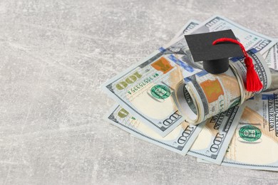 Photo of Scholarship concept. Graduation cap and banknotes on light grey table, closeup with space for text