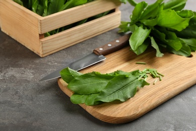 Photo of Fresh cut sorrel leaves and knife on grey table