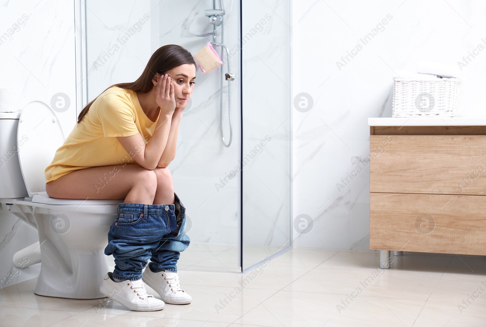 Photo of Upset woman sitting on toilet bowl in bathroom