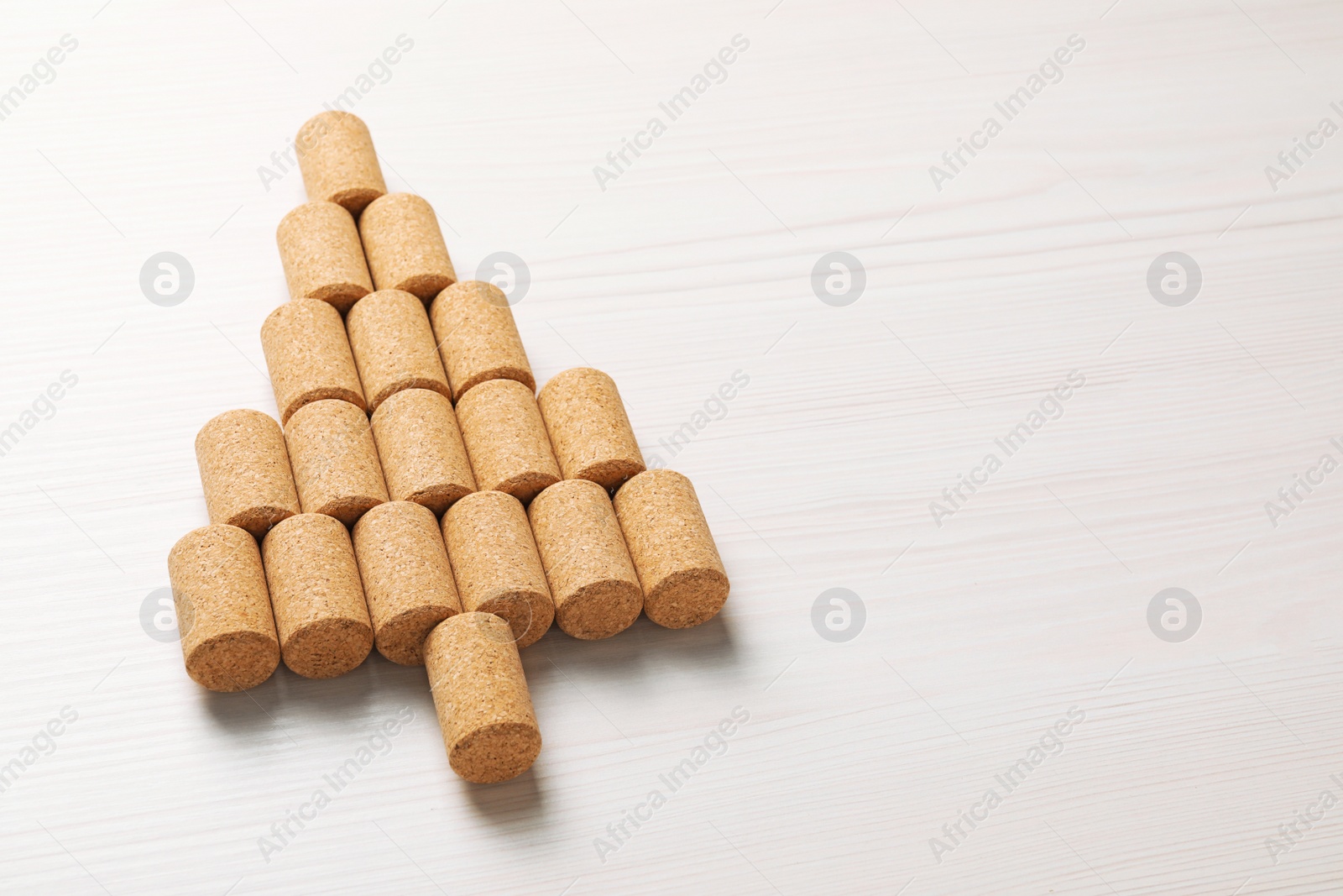 Photo of Christmas tree made of wine corks on white wooden table. Space for text