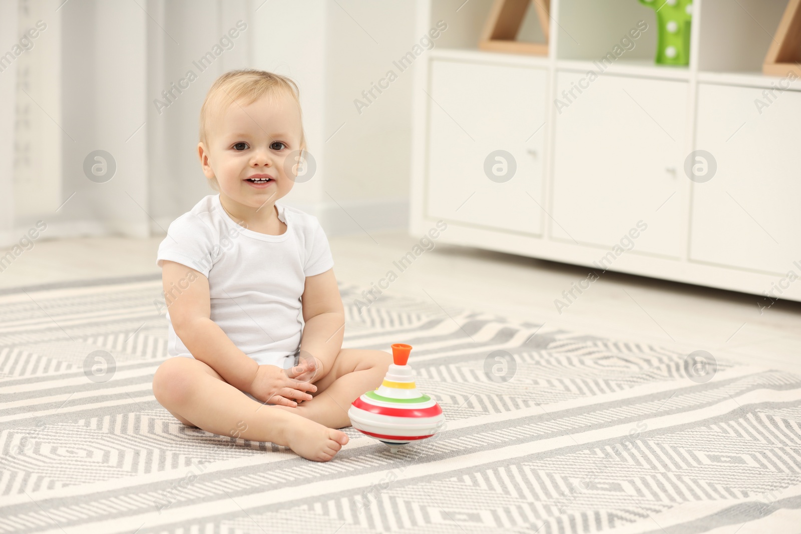 Photo of Children toys. Cute little boy and spinning top on rug at home