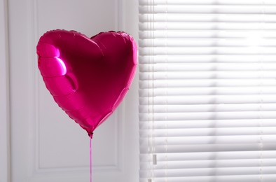 Photo of Festive heart shaped balloon in light room. Space for text