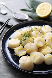 Photo of Raw scallops with thyme and lemon zest on grey marble table, closeup