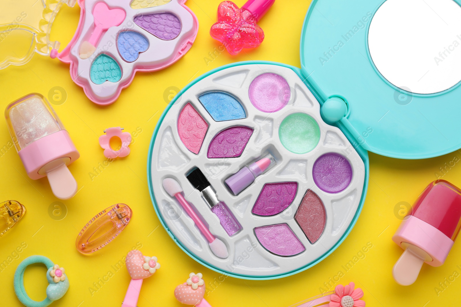 Photo of Eye shadow palette and other decorative cosmetics for kids on yellow background, flat lay