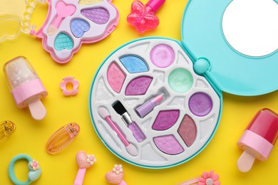 Photo of Eye shadow palette and other decorative cosmetics for kids on yellow background, flat lay