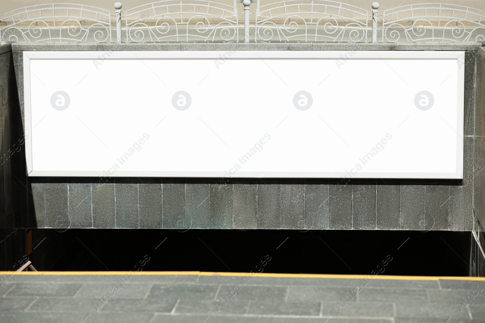 Photo of Blank advertising board hanging on wall near underground passage