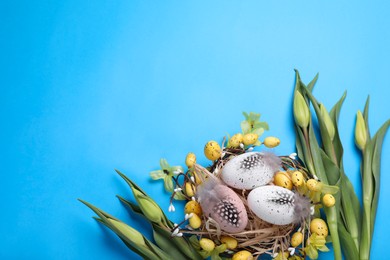 Photo of Flat lay composition with flowers and eggs on light blue background, space for text. Easter celebration