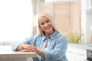 Portrait of happy mature woman at table indoors