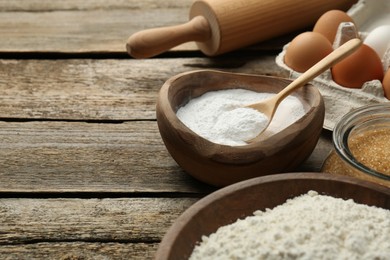 Photo of Ingredients for making dough and rolling pin on wooden table, closeup. Space for text