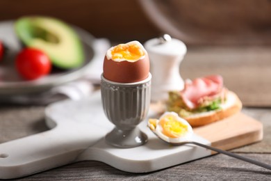 Photo of Soft boiled chicken egg served on wooden table