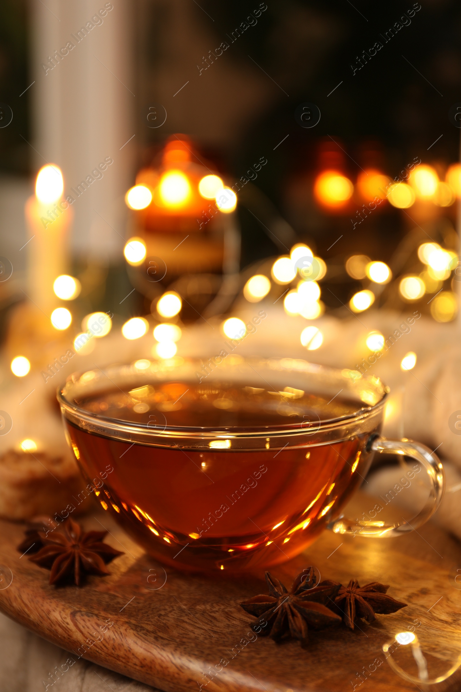 Photo of Glass cup of aromatic anise tea on wooden board indoors, bokeh effect