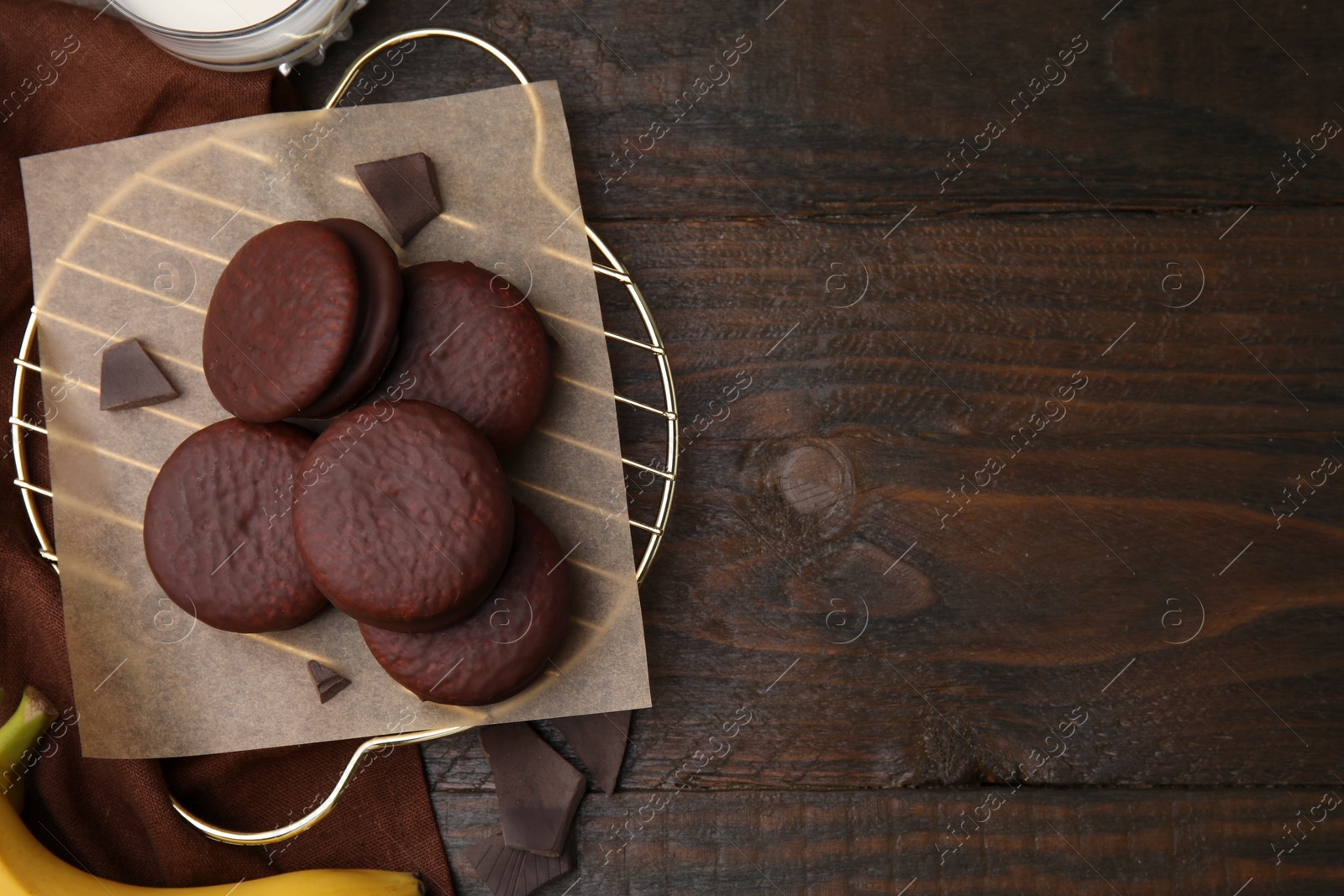 Photo of Delicious choco pies, bananas and glass of milk on wooden table, flat lay. Space for text