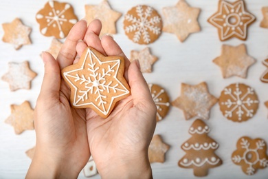 Photo of Woman holding tasty homemade Christmas cookie decorated with icing, top view