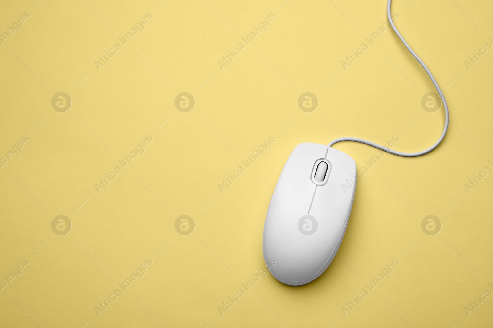Photo of Wired computer mouse on yellow background, top view. Space for text