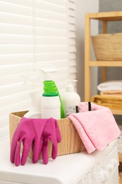 Photo of Different cleaning products in wooden box on washing machine indoors
