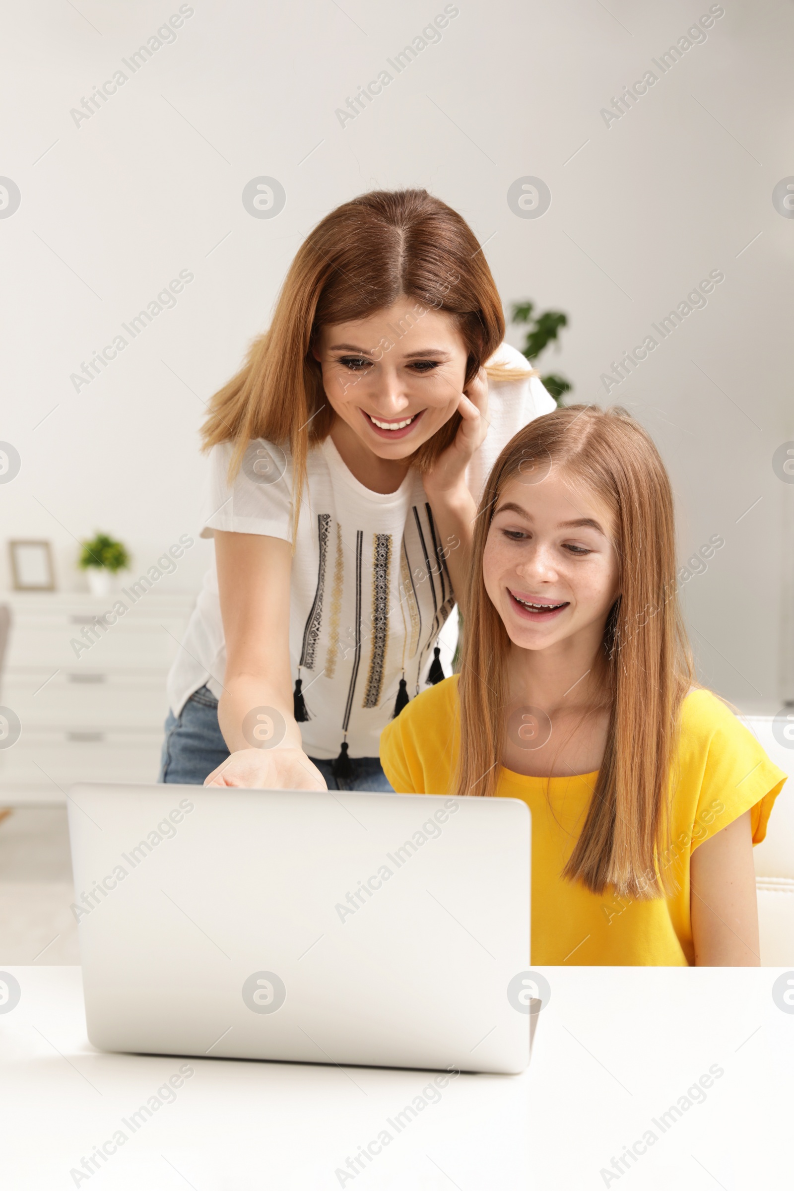 Photo of Happy mother and her teenager daughter with  laptop at home