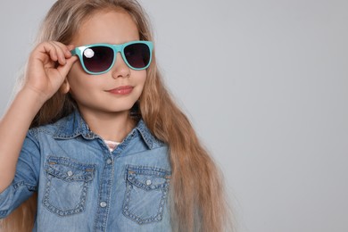 Photo of Girl in stylish sunglasses on light grey background. Space for text
