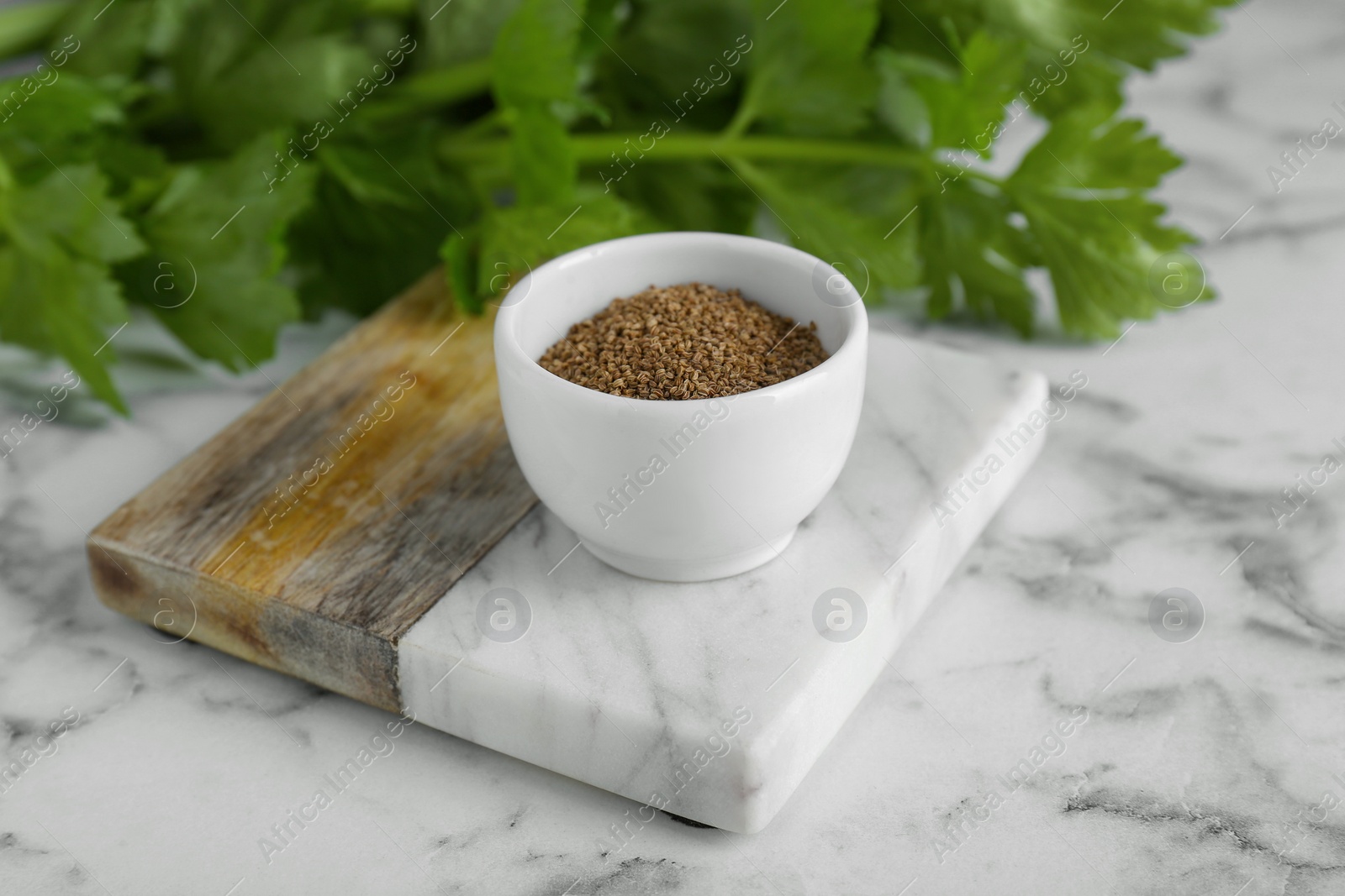 Photo of Bowl of celery seeds on white marble table