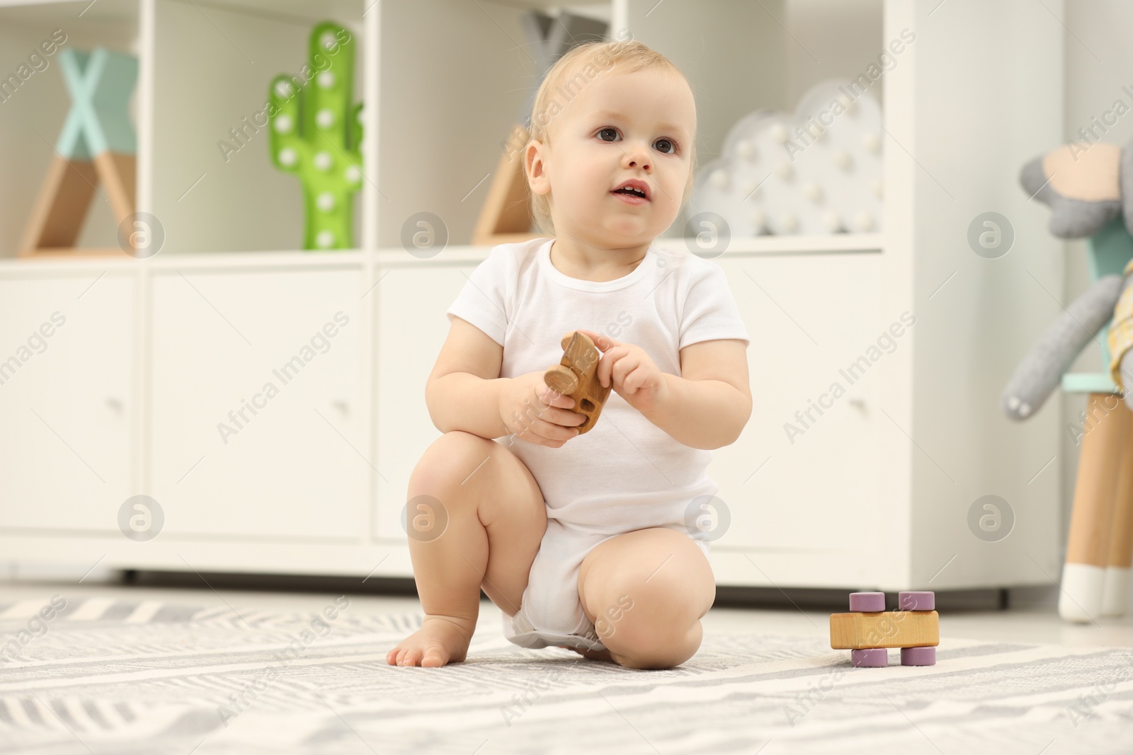 Photo of Children toys. Cute little boy playing with wooden car on rug at home