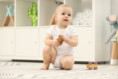 Photo of Children toys. Cute little boy playing with wooden car on rug at home