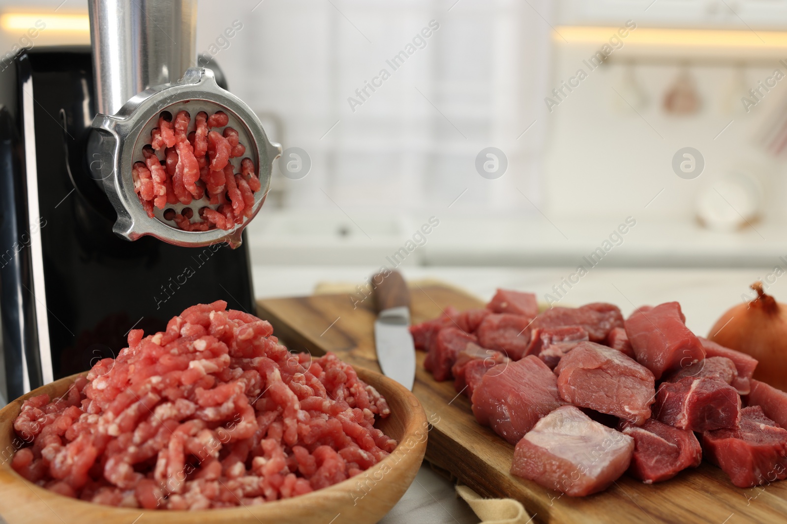 Photo of Electric meat grinder with beef on white table indoors