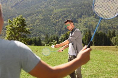 Friends playing badminton in mountains on sunny day
