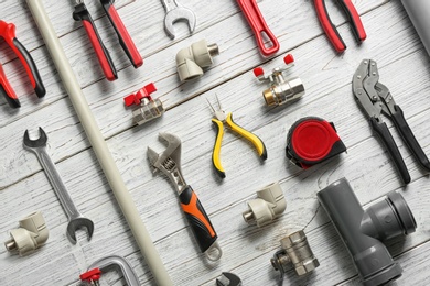 Flat lay composition with plumber's tools on white wooden background