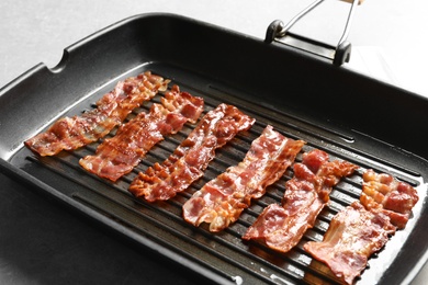 Photo of Grill pan with bacon on table