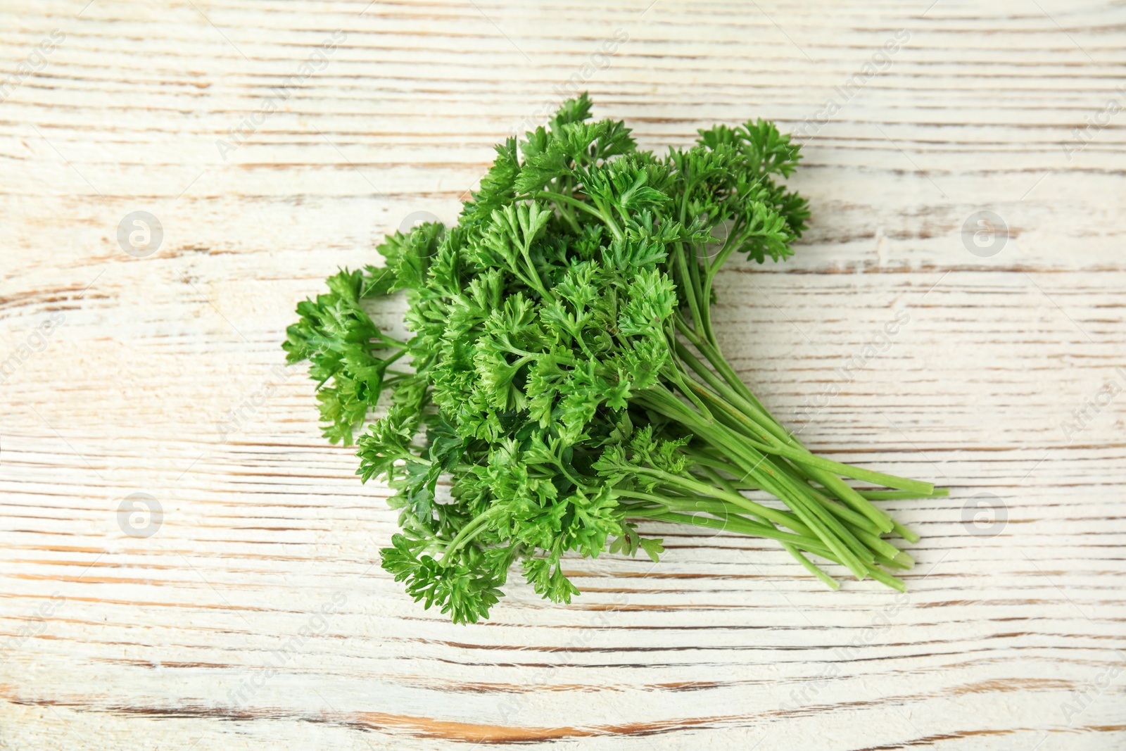 Photo of Bunch of fresh green parsley on white wooden background, above view