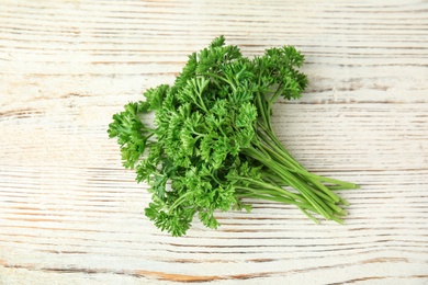 Photo of Bunch of fresh green parsley on white wooden background, above view