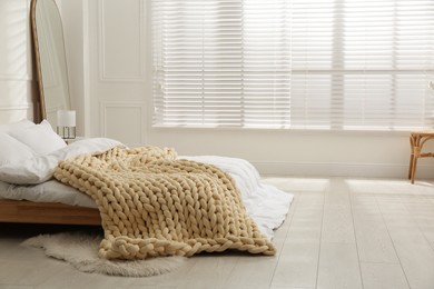 Photo of Soft chunky knit blanket on bed in light room