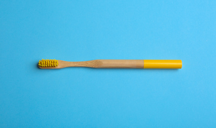Toothbrush made of bamboo on light blue background, top view