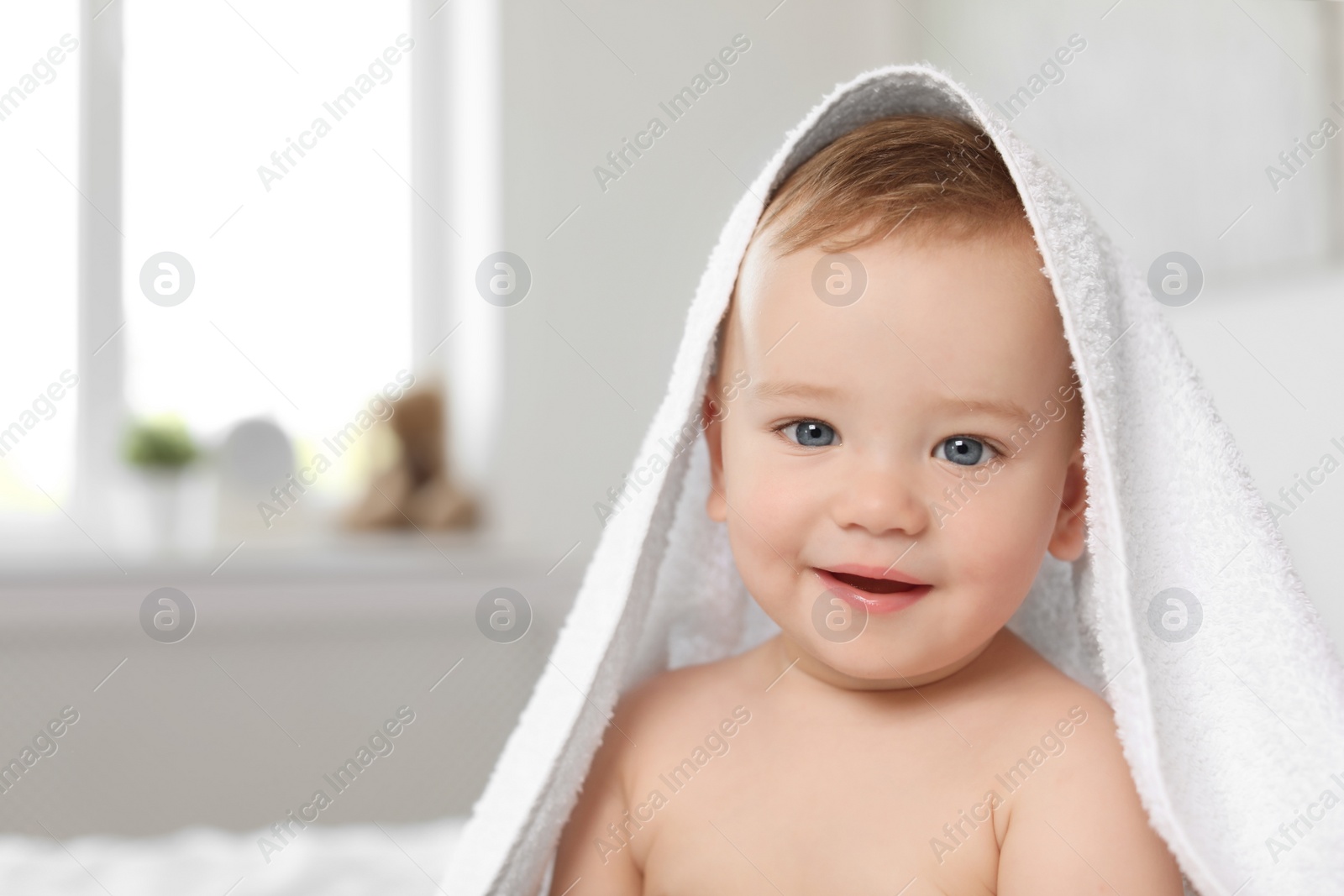 Photo of Adorable little baby with white towel indoors