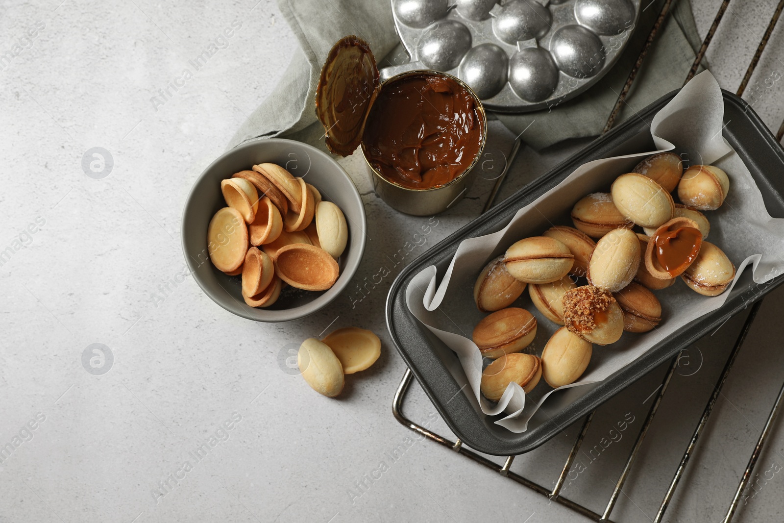 Photo of Delicious walnut shaped cookies with condensed milk on grey table, flat lay. Space for text