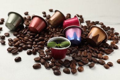 Photo of Coffee capsules with seedling and beans on white marble table