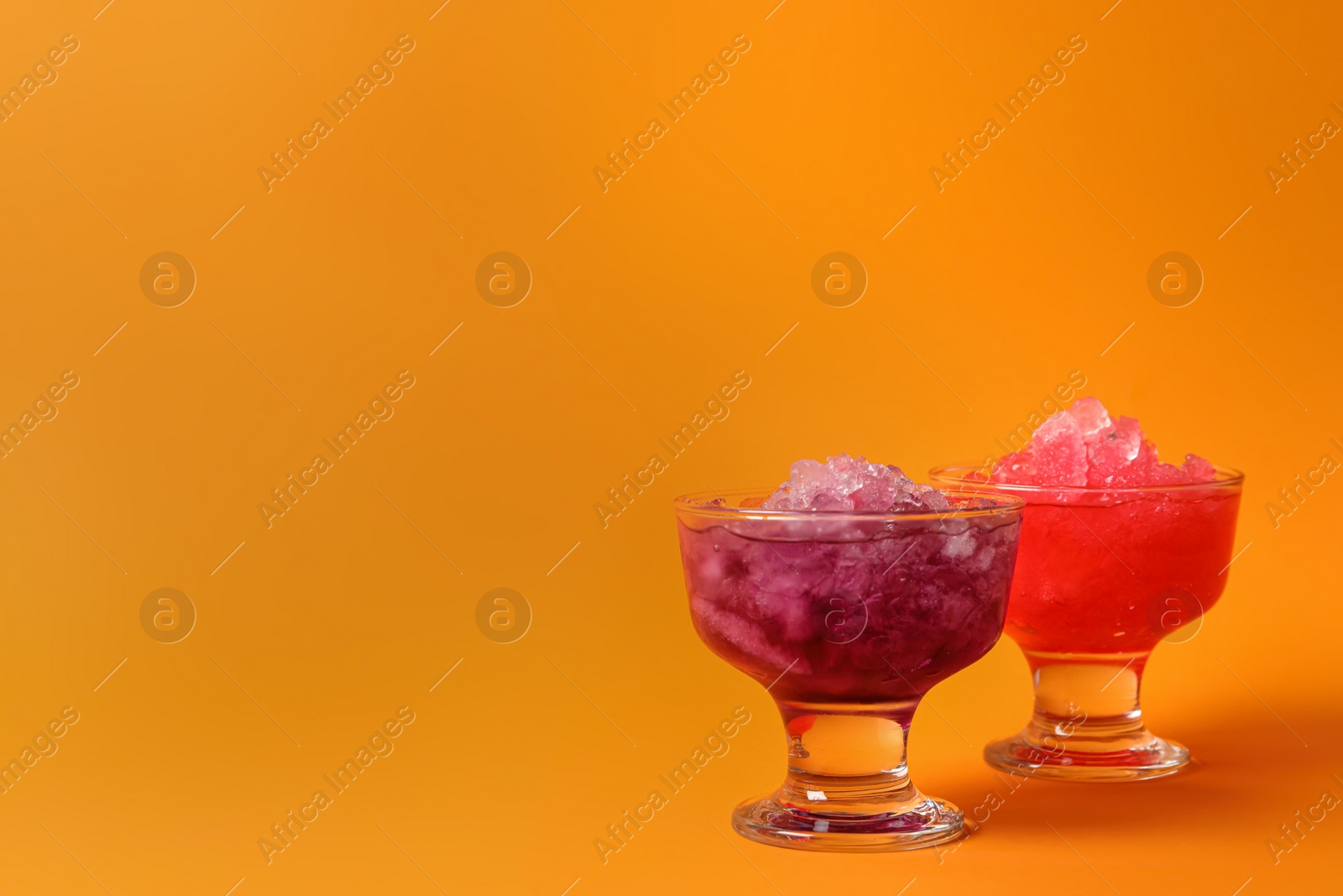 Photo of Shaving ice in glass dessert bowls on orange background, space for text