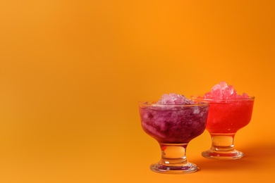 Photo of Shaving ice in glass dessert bowls on orange background, space for text