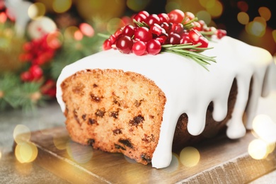 Traditional classic Christmas cake decorated with cranberries on wooden board, closeup. Bokeh effect