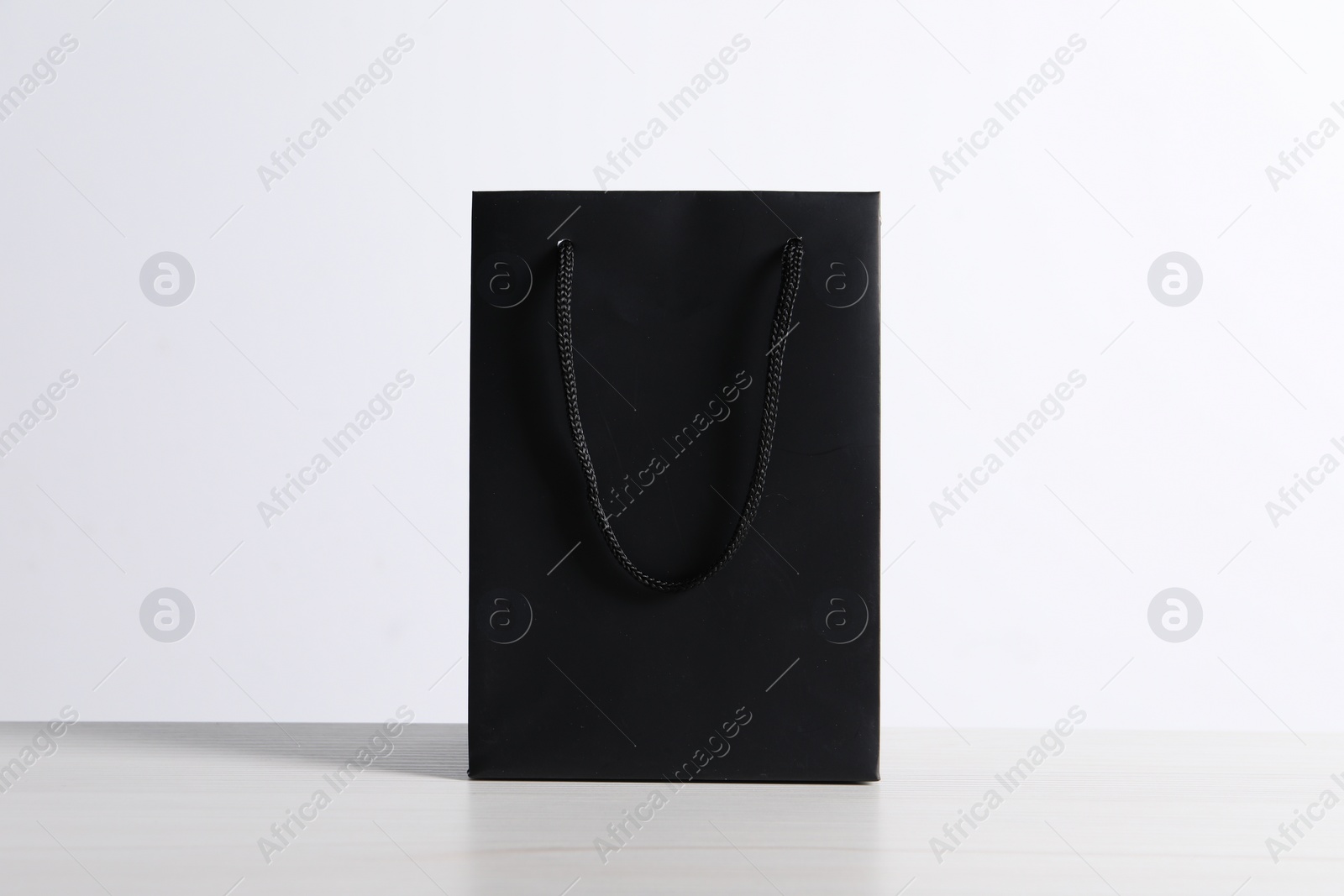Photo of Black paper bag on white wooden table