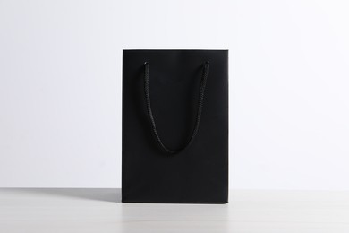 Black paper bag on white wooden table