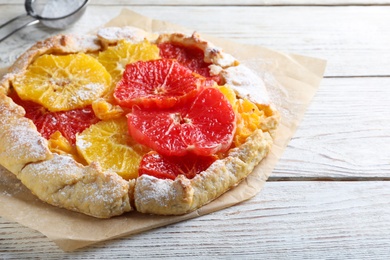 Photo of Delicious galette with citrus fruits on white wooden table, closeup