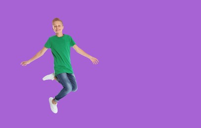Image of Happy boy jumping on violet background, space for text
