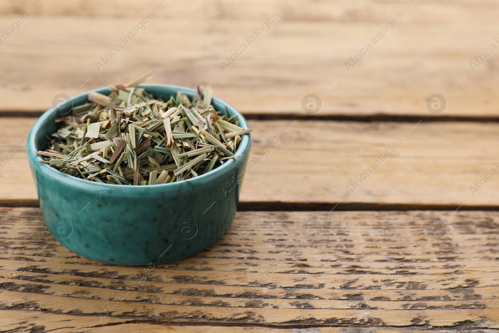 Photo of Bowl with aromatic dried lemongrass on wooden table, space for text